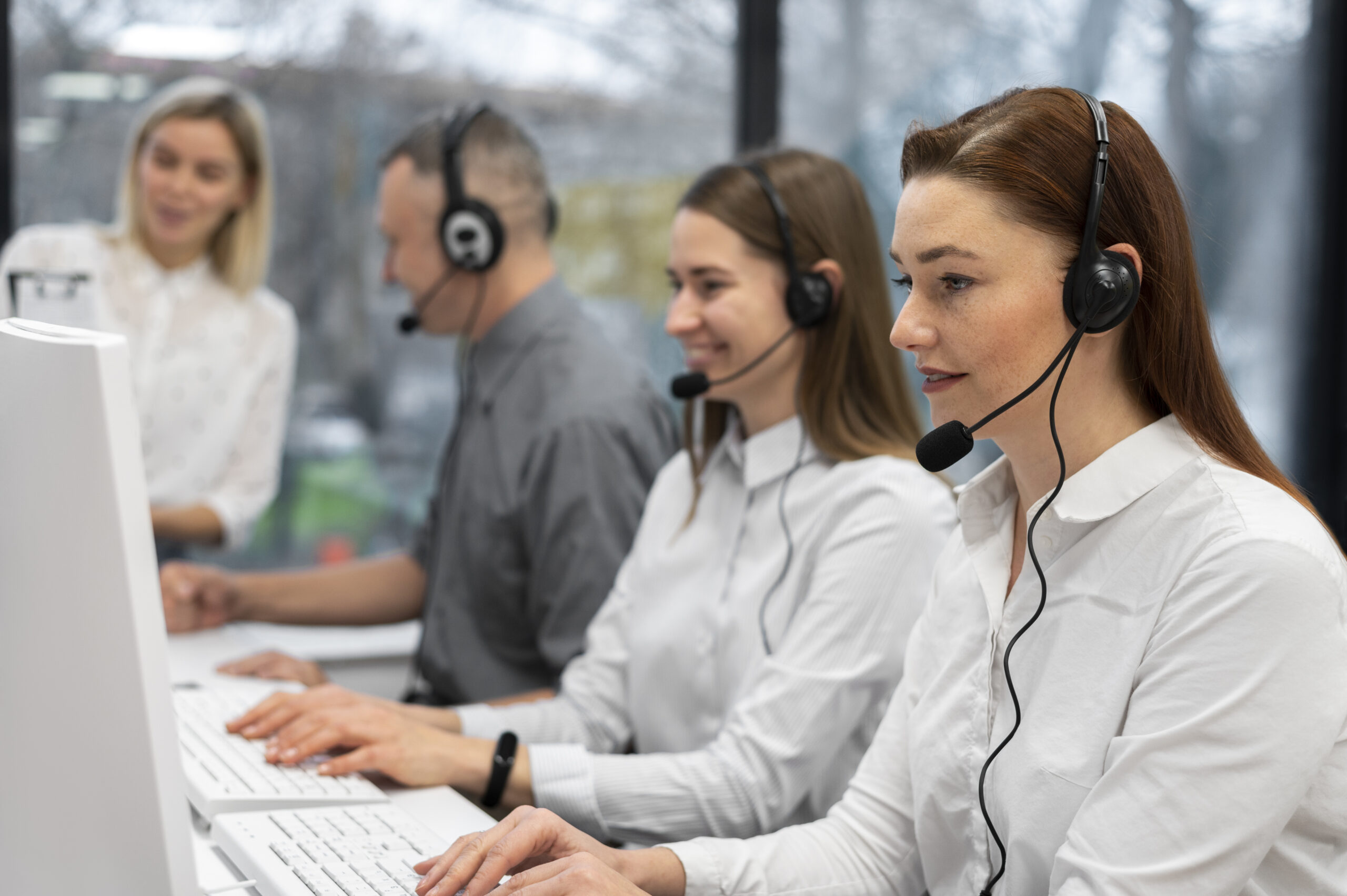 colleagues-working-together-call-center-with-headphones-scaled
